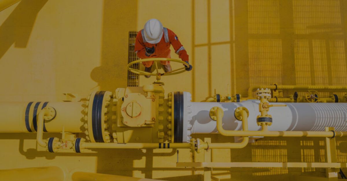 a worker on a platform next to a yellow pipe