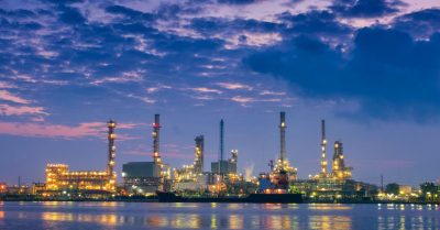 a landscape photo of a refinery or a factory in nighttime, from far away