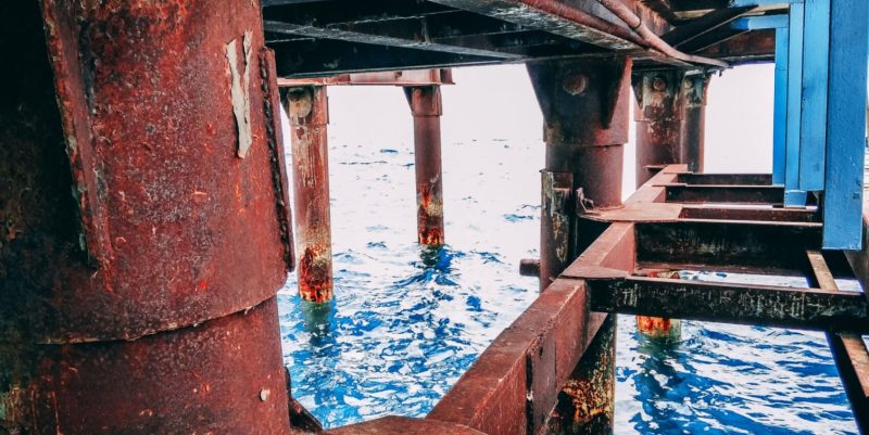 primer plano de un poste de refinería corroído en el océano, cenosco rbi