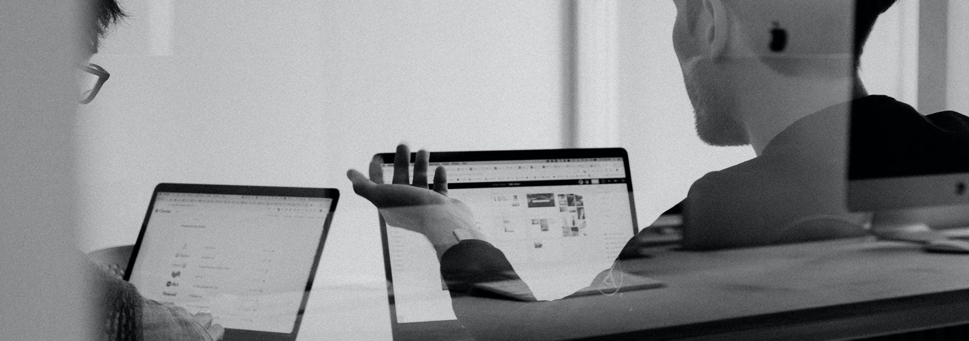 black and white photo of two teammates working together on their laptops